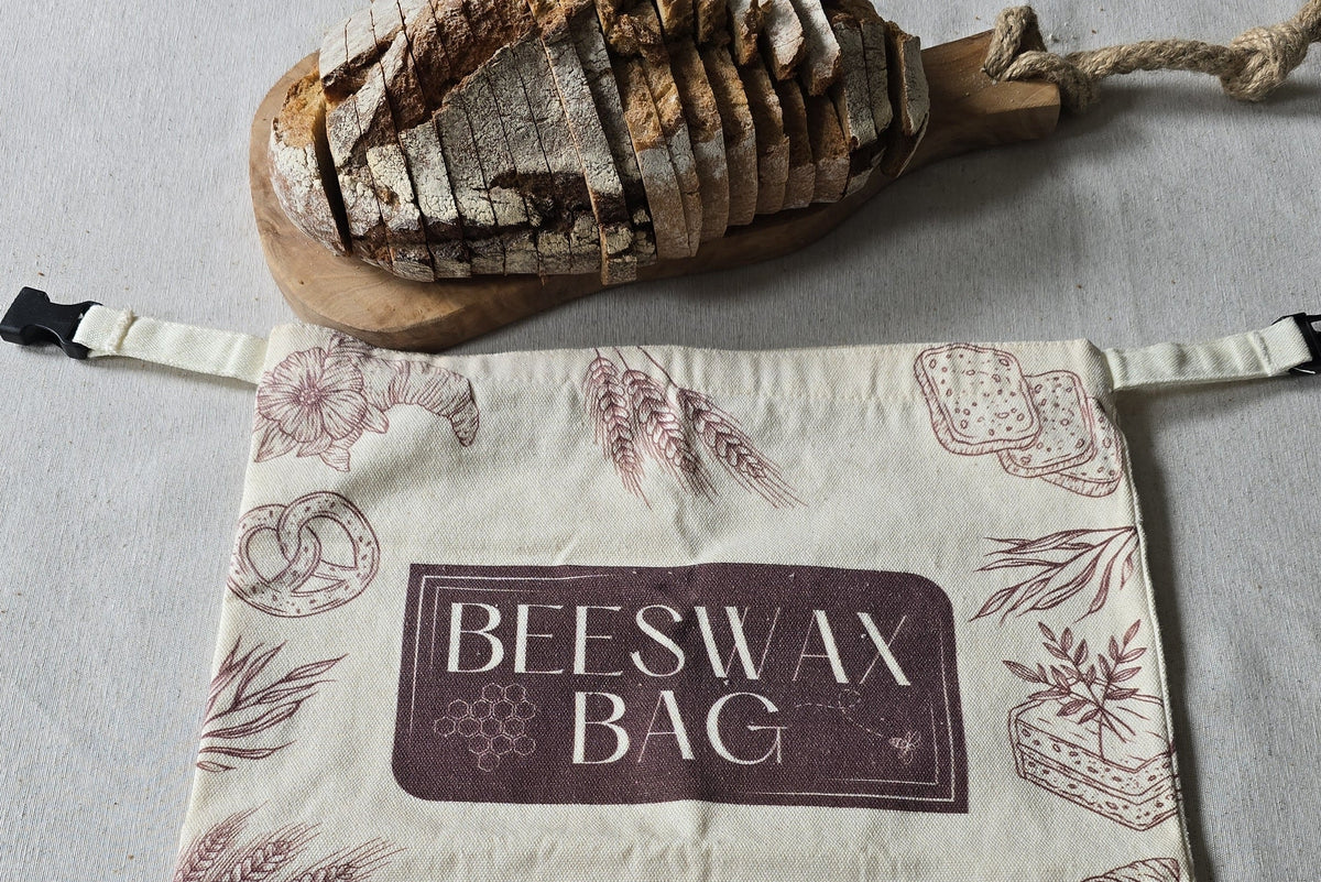Gesneden brood op een houten snijplank naast een bijenwas broodzak